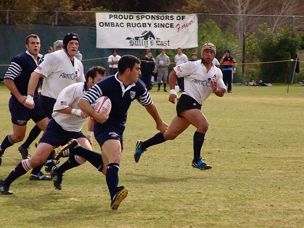 An OMBAC player breaks the line in front of a club sponsor banner